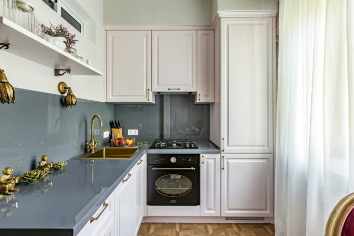 маленькая кухня с белой мебелью, серыми столешницами и фартуком из того же материала